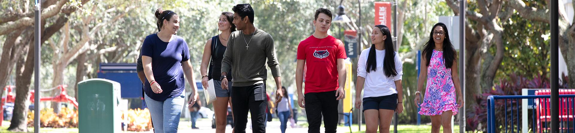 Students walking across the Jupiter campus under trees